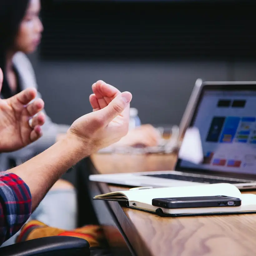 Manos sobre la mesa durante una reunión de trabajo con portátiles