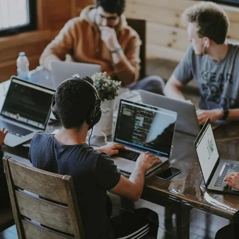 Varias personas trabajando con portátiles en una mesa compartida