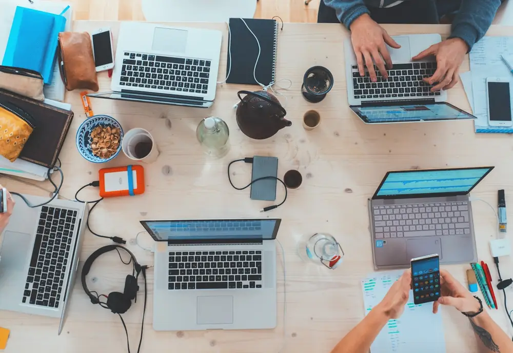 Vista cenital de una mesa con portátiles, tabletas y libretas durante una sesión de trabajo