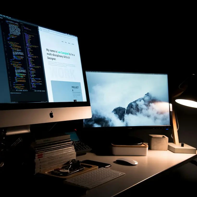 Escritorio con dos monitores mostrando el diseño de una página web en curso